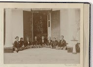 Acht jongemannen gezeten op de vloer bij een ingang van een gebouw