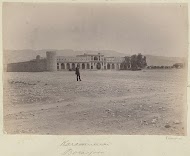 Gezicht op een karavanserai in Perzië met op de voorgrond een man op een vlakte