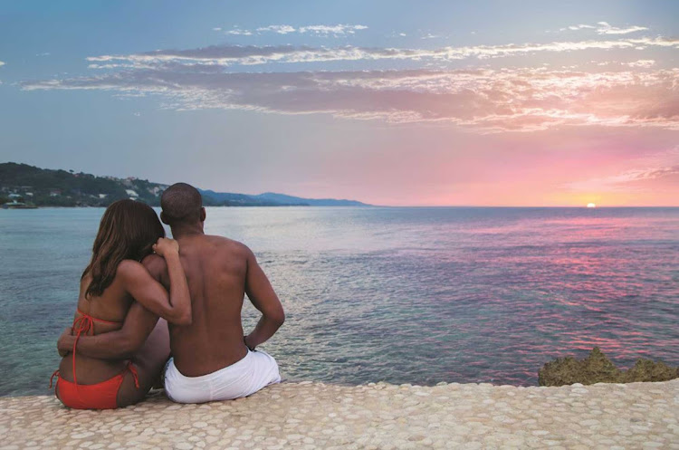 A couple watches one of Jamaica's scenic sunsets. 