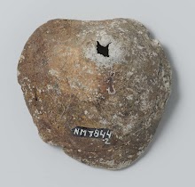 Fragment bestaande uit een klompje lood met in het midden een gaatje