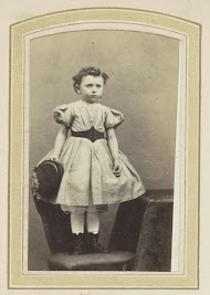 Portret van een meisje in een jurk met ceintuur op een stoel