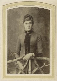 Portret van een vrouw in een jurk bij een hek