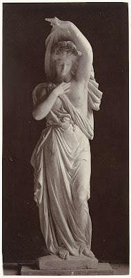 Marmeren beeld van een vrouw in toga met gedeeltelijk ontbloot bovenlichaam.