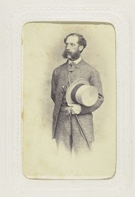 Studioportret van een man in kostuum met een wandelstok en handschoenen in zijn hand en een hoge hoed rustend op zijn arm