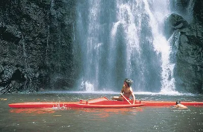 A Tahitian man kayaks near a waterfall on Tahiti. Visitors are encouraged to do the same. 
