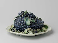 Botervloot in de vorm van een blauwe druiventros, bevestigd op een bord