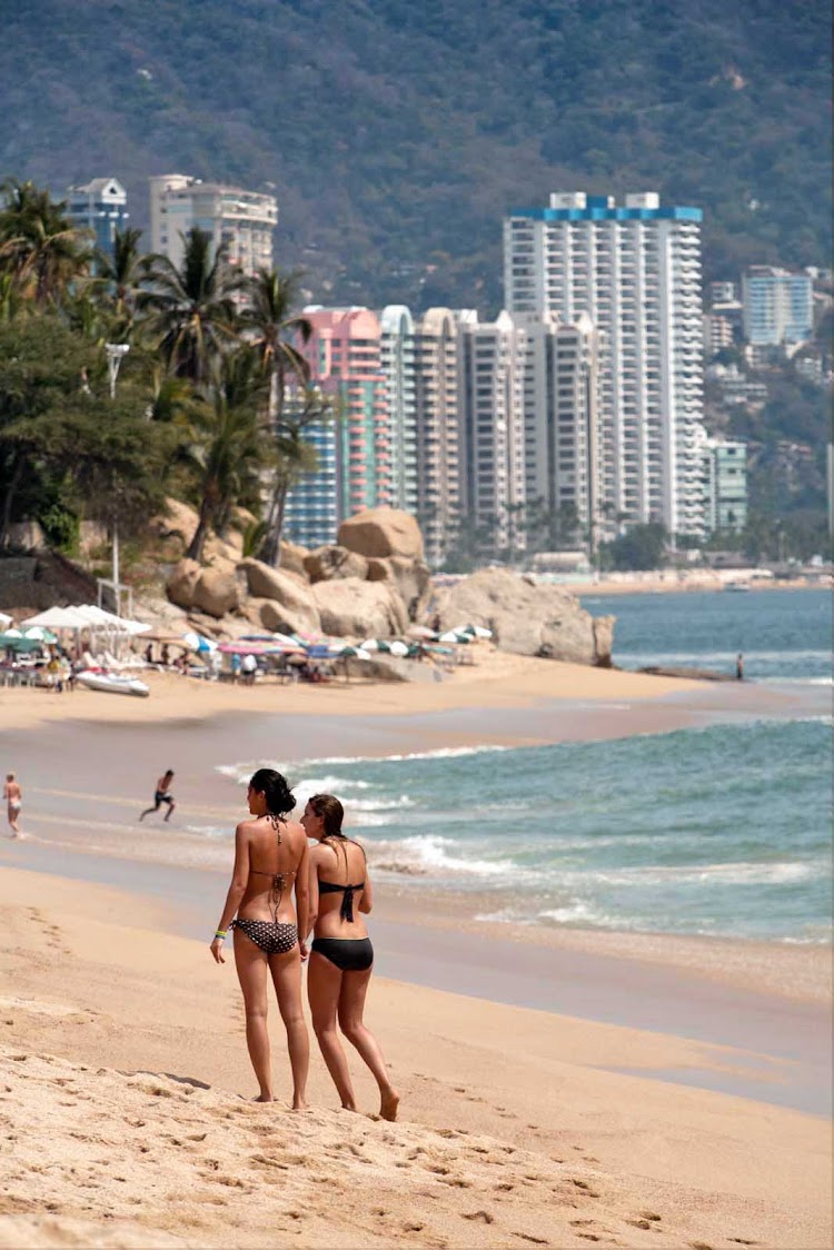 Two women walk on Acapulco's world-famous beach.