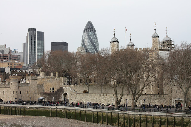 Londýnský Tower při pohledu z Tower Bridge - v dálce je vidět známá budova nazýváná Okurka.
