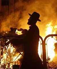 An Ultra-Orthodox Jew walks past burning garbage during a protest against the digging up of ancient graves in Jerusalem's Mea Shearim neighbourhood