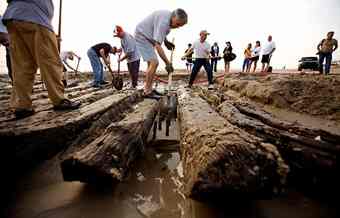 Volunteers and members of the North Carolina Wildlife Resources Commission use fire hoses, hand shovels and heavy equipment to remove the sand and pull what remains of a shipwreck off the beach in Corolla, N.C. on Tuesday, April 6, 2010. The wreck could be the oldest shipwreck on the Carolina coast. (L. Todd Spencer | The Virginian-Pilot) 