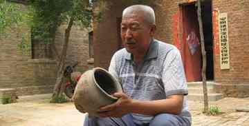 Long Zhenshan, 64, a farmer and antiques collector, shows off an ancient cooking pot, one of more than 3,000 pieces he has found.
