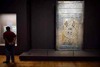 A man studies an antiquity at the Louvre's "Roads of Arabia" exhibition in Paris