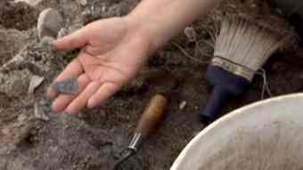 A worker at the archeological dig in Sheshatshui, Labrador, holds the tip of a broken arrowhead that was found at the site.