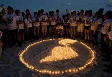 Members of WWF make a representation of the Earth with lit candles in a beach in Cancun.