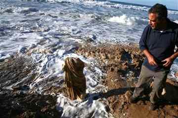 An Israeli man stands next to a 1,700-year-old statue after it was found on the beach in the costal city of Ashkelon, Tuesday, Dec. 14, 2010. Israel's antiquities authority says a storm that raked over part of an archaeological dig this week has exposed a 1,700-year-old statue. The headless marble statue of a woman was found buried in the sand by a resident walking near the shore in the southern city of Ashkelon. 