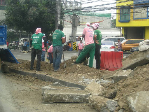 Metropolitan Manila Development Authority (MMDA) workmen clearing road rubble after uprooting acacia trees along Katipunan Avenue