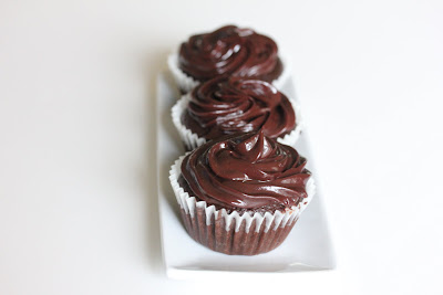 photo of three chocolate cupcakes with chocolate ganache frosting on a plate