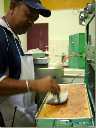 pressing down last layer of sarawak layer cake - copyright house of annie