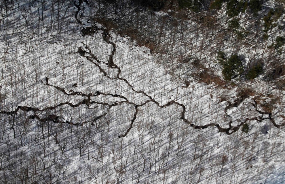 [Las grietas se ven en el suelo cubierto de nieve en los bosques y cerca de la ciudad devastada por el tsunami del terremoto de Sendai 12 de marzo[5].jpg]