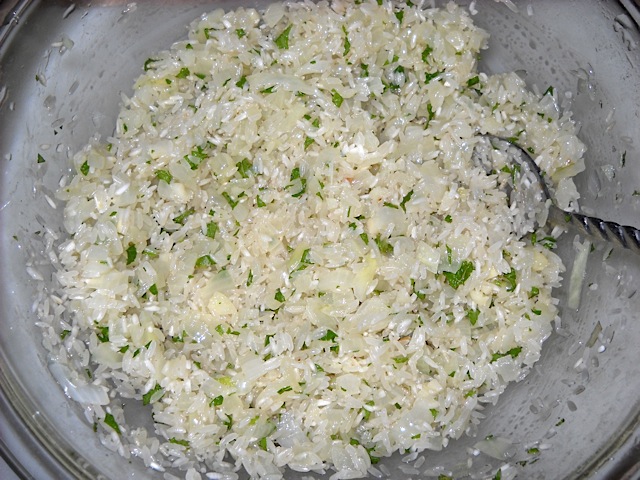 rice filling (uncooked rice, onions, garlic, lemon juice, salt and fresh mint) in clear mixing bowl 