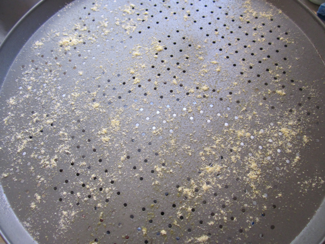 pizza pan coated with non stick spray and corn meal 