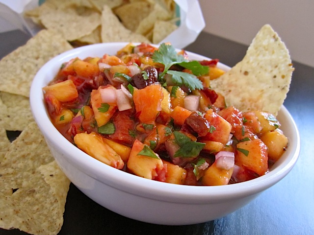 Chipotle Peach Salsa in white bowl with tortilla chips on the side