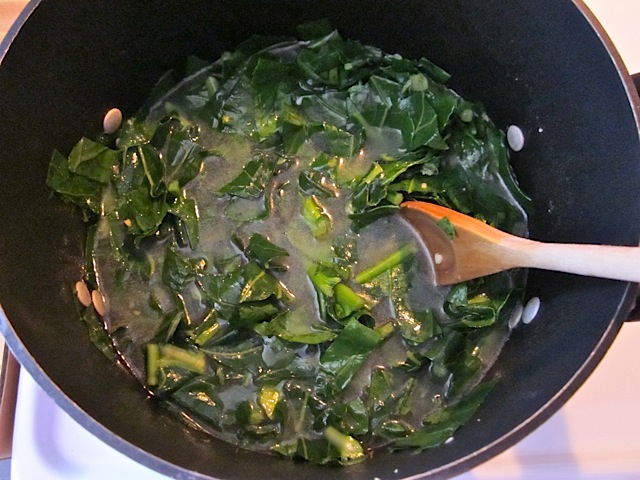 simmering collared greens in pot with wooden spoon 