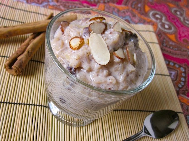 Rice Pudding in cup with spoon and cinnamon sticks on side 