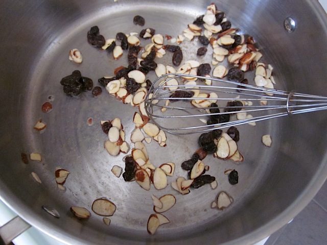toasted almonds and raisins in pot with whisk 