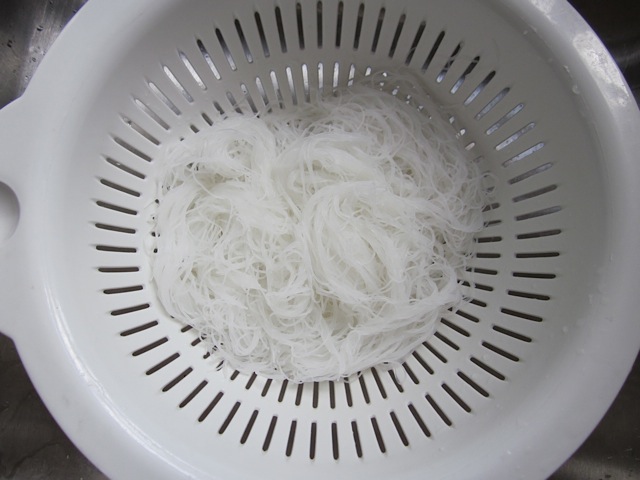 draining rice noodles in strainer 