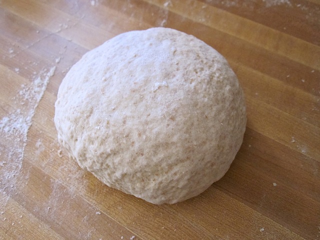 kneaded dough formed into ball and on floured countertop