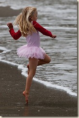 Cute Little Girl in Pink Dances on the Beach during the Kite Festival.