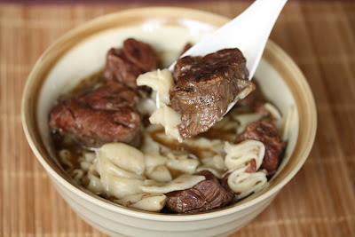 close-up photo of a spoonful of beef noodle soup