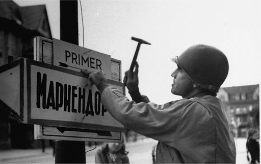 Капитан армии США Эрнест Ф. Миллз прибивает на берлинской улице дорожный указатель на русском языке