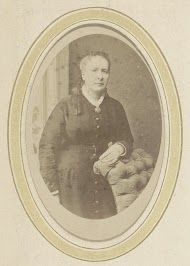 Portret van een vrouw in een jurk leunend op een fauteuil