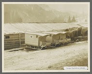 Barak met geparkeerde ambulancesleeën, één heeft een rood kruis