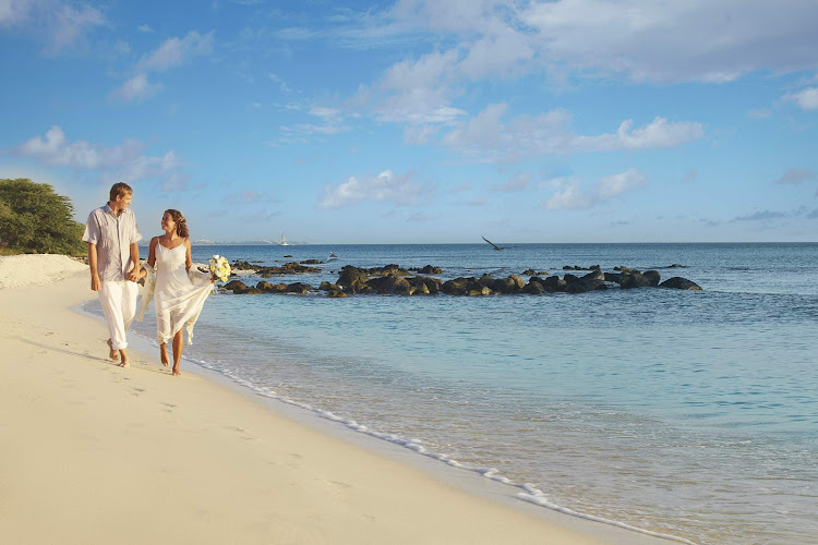 A bride and groom take a quiet stroll on the beach in Aruba.