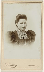 Studioportret van een vrouw met opgestoken haar en een hesje met pofmouwen