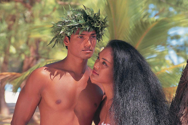 A Tahitian couple in traditional dress are about to greet visitors to their island.