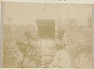 Man met hoge hoed in een draagstoel wordt  gedragen door vier lokale mannen