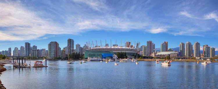False Creek, BC Place and downtown Vancouver high-rise buildings under a blue sky