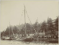 Toeschouwers bij versierde boten aan de Amsteldijk