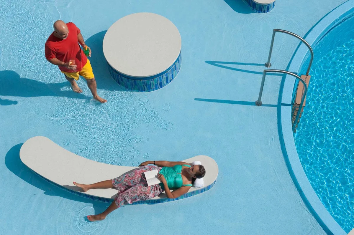 Disney-Dream-guest-lounging-by-pool - Relax and get to that book you've been meaning to read while lounging by the Quiet Cove Pool on Disney Dream.