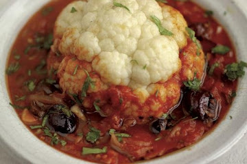 Whole baked cauliflower with tomato and olive sauce