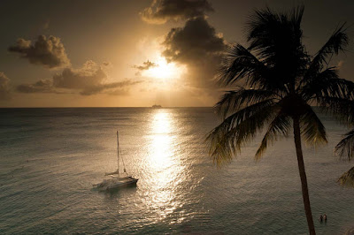 The sun sets on  a catamaran on a quiet bay on Barbados.
