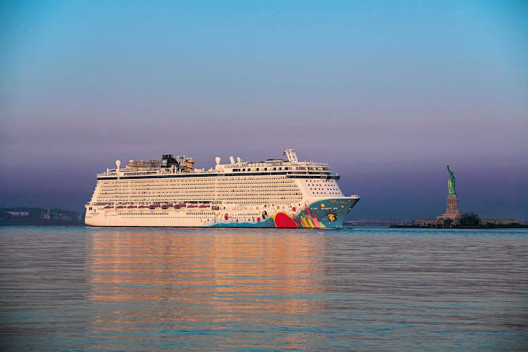 Norwegian Breakaway passes the Statue of Liberty at sunset.