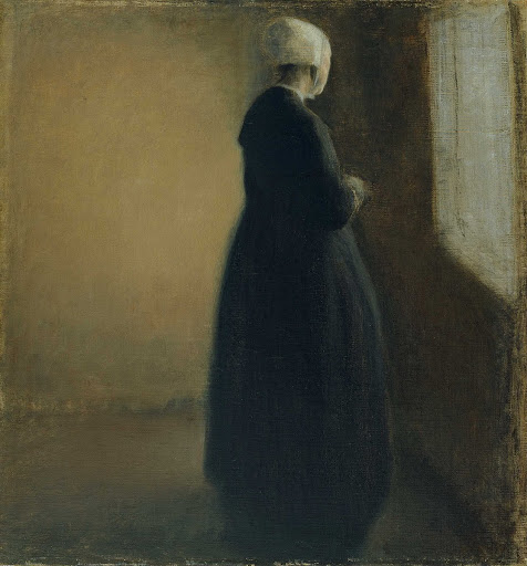 An old woman standing by a window