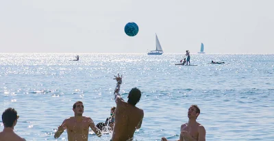 Guys play volleyball on crowded Waikiki Beach, one of the most famous stretches of sand on the planet.