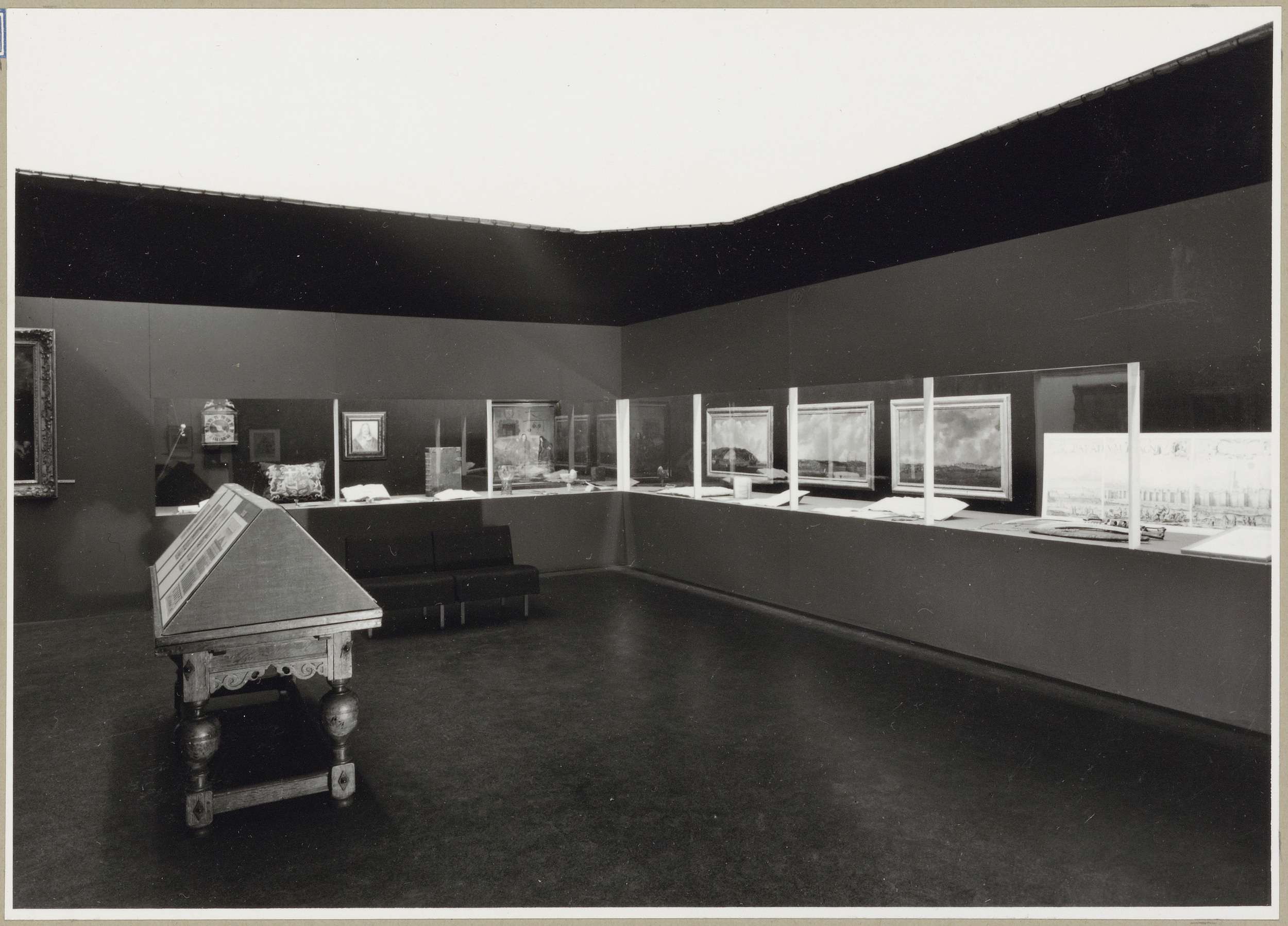 Zaal met verschillende objecten achter een vitrine, links een schuine legkast