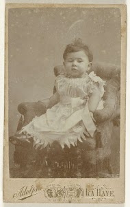 Studioportret van een baby in witte jurk in een stoel